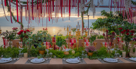 decoration table with flowers, candle and ribbon for romantic dinner at beach