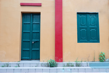 Dark green wood doors and windows on egg colour wall with red line on the wall.