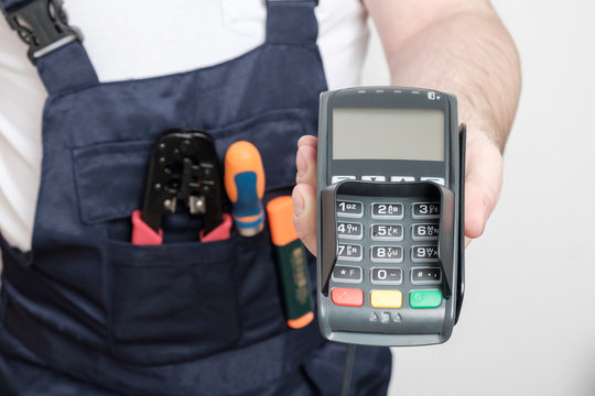 Man with tools holding bank payment terminal - Powered by Adobe