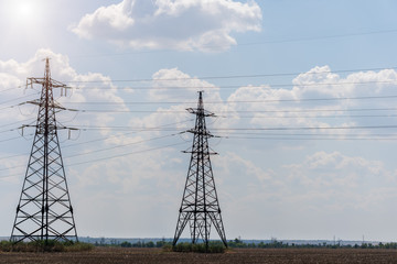 Supports high-voltage power lines against the blue sky. Electrical industry.