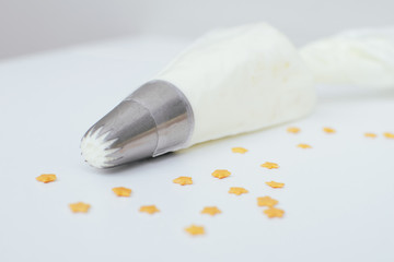 Pastry bag with cream and gold  stars confectionery sprinkling. Picture for a menu or a confectionery catalog.