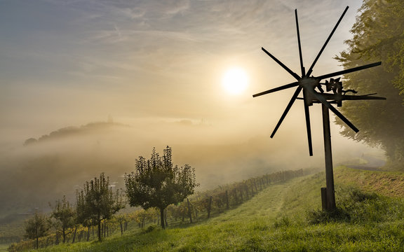 Misty sunset behind a Klapotetz, apple trees and grape hills on the Weinstra&szlig;e  at Gra&szlig;nitzberg near Spielfeld / Leibnitz / Austria