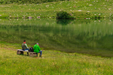 Men fishing on the shore of a small lake mountains