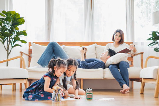 Asian Family With Cute Daughters Painting Art In Living Room At Home