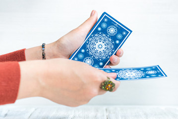 Tarot cards in fortune teller hand on white wooden table background. Future reading.