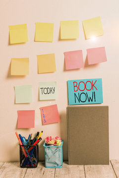 Conceptual hand writing showing Book Now. Concept meaning guaranteed to have place because you have already purchased it Sticky Notes Card on Wall Pencil Pots Notebook on Work Desk