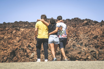 Three teenager playing happy during a school trip in Tenerife, Canary Islands. Young girl embracing...