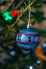 Christmas decoration blue ball hanging on a Christmas tree with a garland on the background