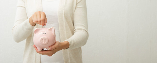 woman hand putting money coin into piggy for saving money wealth and financial concept.