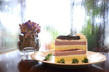 Close up blueberry sponge layer cake topping by blueberry sauce on white plate on wooden table in restaurant, on mirror (have rain water drop) background, look soft and delicious, have copy space