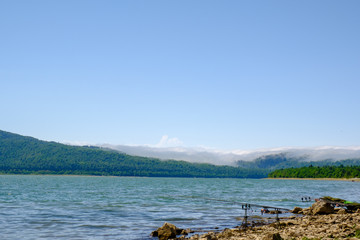 Three feeder fishing rods held in fishing rod holders on the shore of lake Shaori. Peaceful nature landscape on the background.