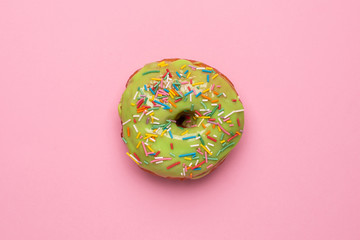 Sweet green donut with sprinkle on a pink background flat lay