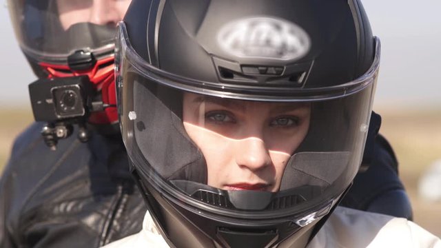 A man and a young woman in sports equipment and a helmet look at the camera