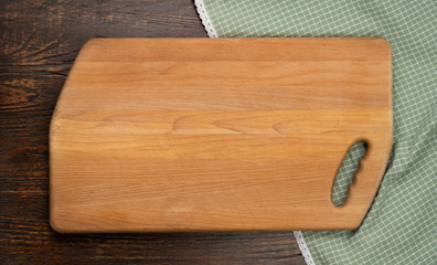 Cutting board over towel on wooden kitchen table. Top view