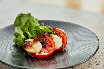Caprese salad on black plate.