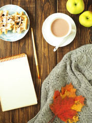 Autumn. flat lay. Sheets, a warm scarf, a Cup of tea and notebook with pen on wooden rustic background.