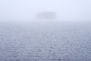 The Island on a foggy lake. Copy space.