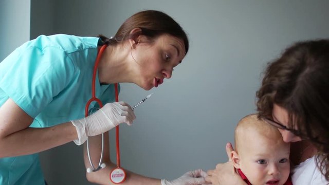 Immunization program, flu shot. The doctor vaccinates the baby sitting in the arms of the mother. Crying baby, medical manipulations, pediatrics concept