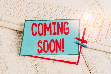 Handwriting text Coming Soon. Conceptual photo event or action that will happen after really short time notebook paper reminder clothespin pinned sheet white keyboard light wooden
