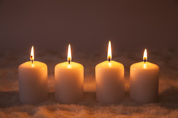 Vier brennende Kerzen im Schnee