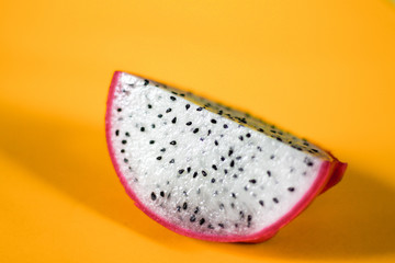 Dragon fruit slice against a bright yellow background showing freshness and pop culture