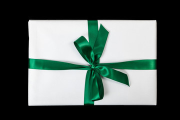 Weißes Weihnachtsgeschenk mit grüner Schleifer vor schwarzem Hintergrund (Draufsicht)