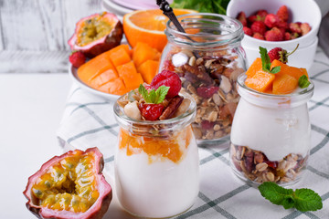 Natural yogurt, granola and mashed passion fruit and mango layered in a glass jar. Breakfast idea