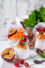 Natural yogurt, granola and mashed passion fruit and mango layered in a glass jar. Breakfast idea