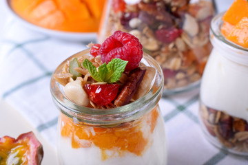 Natural yogurt, granola and mashed passion fruit and mango layered in a glass jar. Breakfast idea