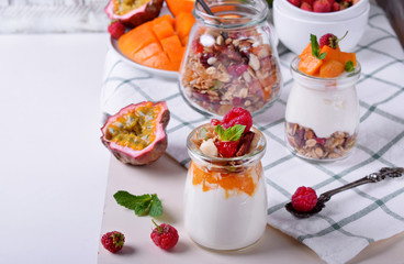 Natural yogurt, granola and mashed passion fruit and mango layered in a glass jar. Breakfast idea