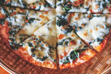Obraz na płótnie Canvas Closeup top angle view half of spinach pizza serve on traditional handcraft dish.