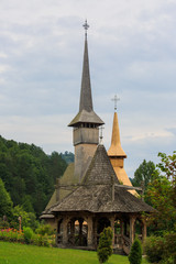 Fototapeta na wymiar Panoramic view of traditional ancient Maramures wooden orthodox church in Transylvania with highest wooden belltower in Europe, Romania. UNESCO world heritage site.
