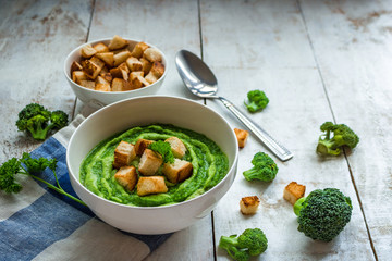 broccoli soup croutons in bowl on white rustic table