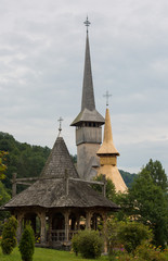 Fototapeta premium Panoramic view of traditional ancient Maramures wooden orthodox church in Transylvania with highest wooden belltower in Europe, Romania. UNESCO world heritage site.