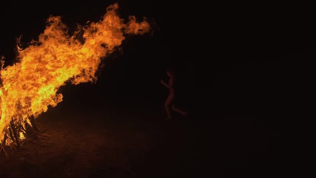 Silhouette of mystic woman in black background of fire fly flame, spark, of contour outline. Outdoor slow motion. Caucasian.