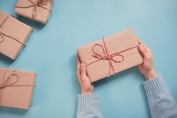 Woman Hands holding craft paper gift box on blue background. for present Christmas, new year,...