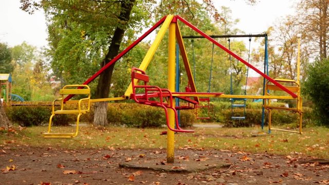 motion of an empty children's carousel. the carousel moves at a minimum speed counterclockwise and stops. autumn. full hd, no sound.
