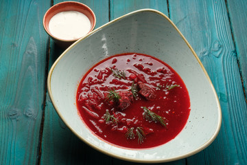 Red beet soup soup with cream, fresh herbs and butter on a blue wooden background Ukrainian cuisine. top view.