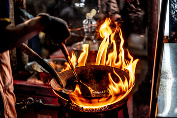 Chef cooking stir fried noodle in a frying pan with chilli peppers,oyster sauce,oil on hot fire from gas in kitchen.Traditional Delicious Thai food.Business,healthy food concept.