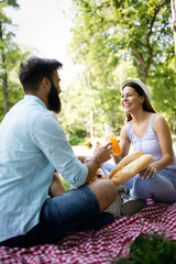 Happy young couple enjoying picnic in park.