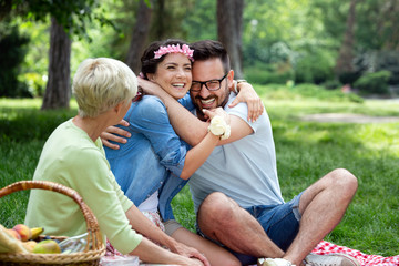 Young woman and man with grandmother smilling in a park on a sunny day