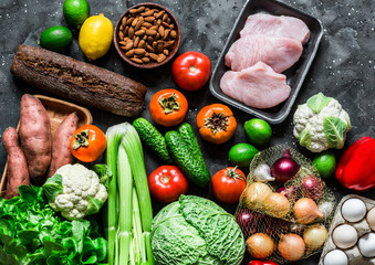 Healthy diet food set. Fresh organic vegetables, fruits, turkey meat, eggs, whole wheat bread on a dark background, top view.  Homemade menu planning