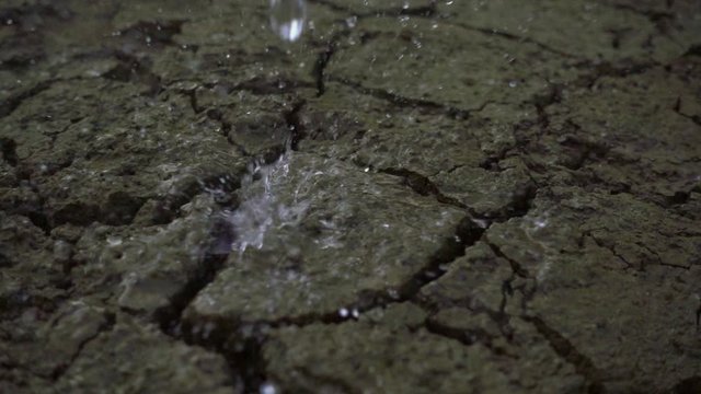 Raining on cracked ground of earth. Slow motion