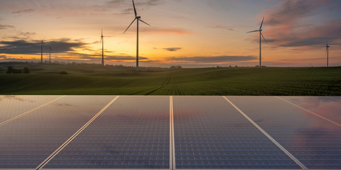 clean energy concept, photovoltaic panels and wind turbines in the light of the rising sun