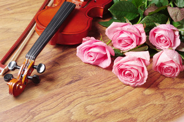 Fototapeta premium Violin and a bouquet of five pink roses on a wooden texture background.