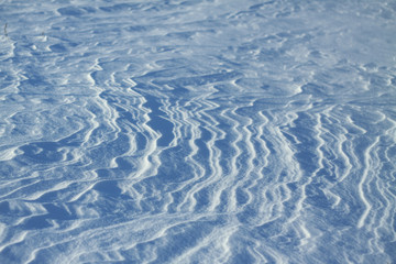 Snow-white snow and the earth sheltered by it. Countryside and snowfall. Winter dunes and mountains of snowflakes. Stock background.