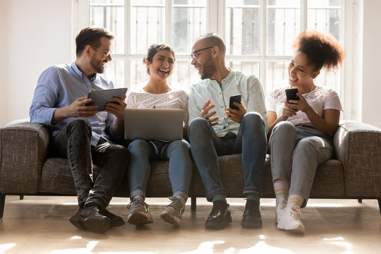 Happy diverse friends using devices, having fun, discussing news