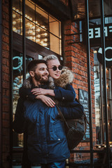 Attractive blond woman in sunglasses is hugging her handsome man on the street.