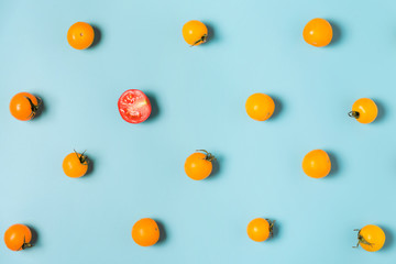 Half of red tomato cherry stand out from yellow tomatoes cherry. individuality and difference...