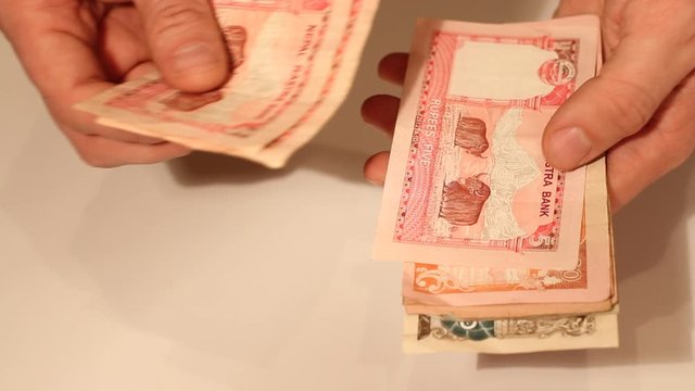 Man's hands counting Nepalese Rupee banknotes. National Currency of Nepal (NPR)
